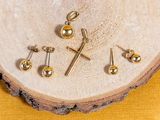 three pairs of gold cross stud earrings on a piece of wood