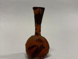 un petit vase posé sur une surface blanche