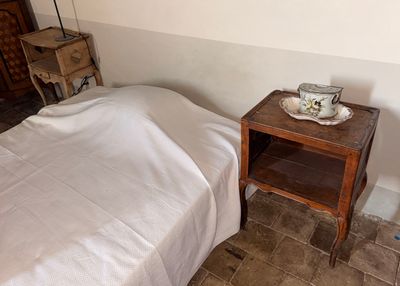 un lit recouvert d'une couverture blanche et une petite table sur laquelle se trouve un bol
