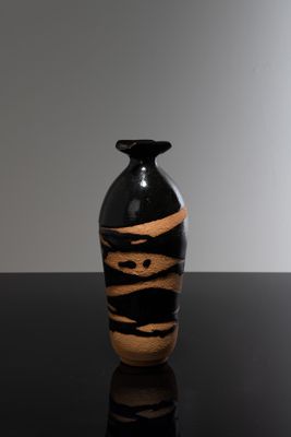 un vase noir et marron posé sur une table noire