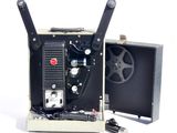 un vieux projecteur de cinéma posé sur une surface blanche