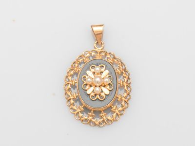 un pendentif en or jaune orné d'une pierre bleue entourée de filigrane