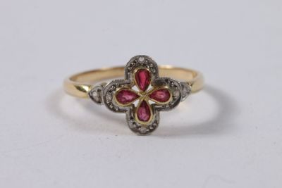 une bague en or jaune sertie d'un rubis en forme de fleur et de diamants