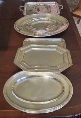 quatre plateaux en argent posés sur une longue table en bois