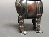 a small metal statue of a dog with a bowl on it ' s head