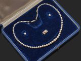 un collier de perles et une paire de boucles d'oreilles présentés dans un écrin en velours bleu