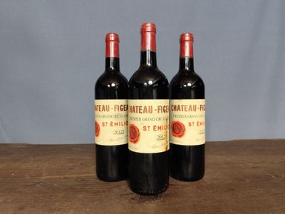 three bottles of red wine sitting on top of a wooden table