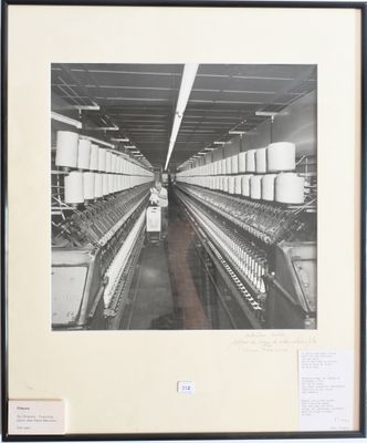 photographie en noir et blanc d'une usine où l'on voit une rangée de métiers à filer