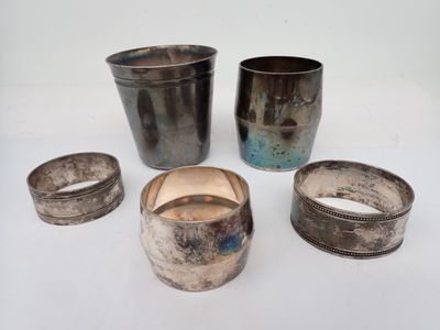 several silver cups and napkins sitting on a white surface