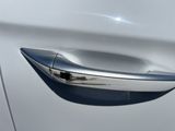 the door handle of a white car with a shiny chrome finish
