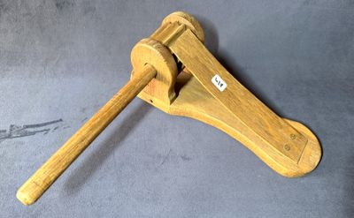 une pince en bois munie d'un manche en bois, posée sur une surface grise