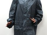 woman wearing a blue rain coat standing next to a white wall