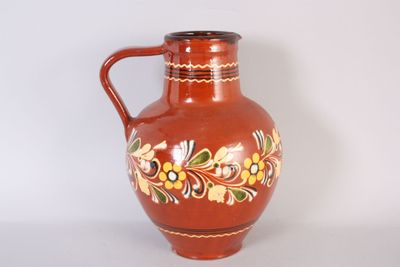 a red vase with a floral design on it