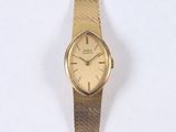 a gold wrist watch with a gold band on a white surface