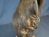 a person holding a fake bird with a long hair on it ' s head