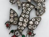 a close up of a brooch with a bird and flowers on it