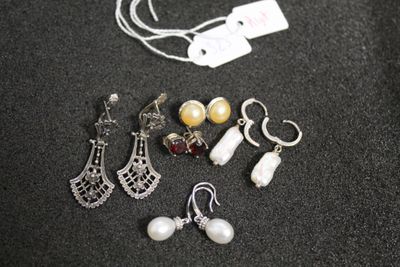cinq paires de boucles d'oreilles et un collier posés sur une table