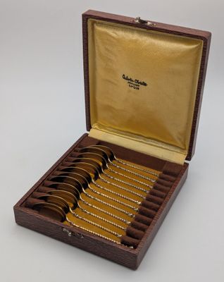 six cuillères dans une boîte en bois avec un couvercle doré