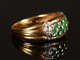 a close up of a gold ring with green stones on a black surface