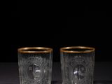 a pair of etched glass tumblers with gold rims