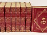six red books are lined up in a row on a white surface