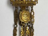 une horloge en or accrochée au mur, entourée d'une chaîne