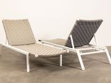pair of lounge chairs in a room with concrete flooring and a white wall
