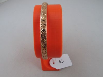 an orange bang bracelet with a gold plated design on it