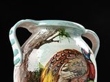 a vase with a bird painted on it sitting on a table