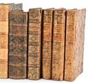 several old books are lined up in a row on a white surface