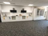 a room with a tv, cabinets, and a desk in it
