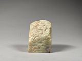 a white jade carving of a dragon on a rock