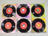 four black vinyl records on a white table with a red label
