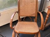 un fauteuil à bascule en bois avec une assise en osier, placé devant une fenêtre