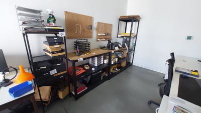 une pièce avec un bureau, des étagères et un ordinateur posé dessus
