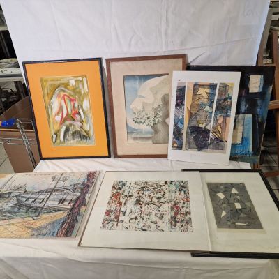 une table sur laquelle sont posées plusieurs œuvres d'art encadrées