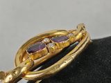 a close up of a gold broochle on a black hat