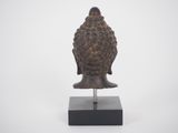 an image of a statue of a buddha head on a wooden base