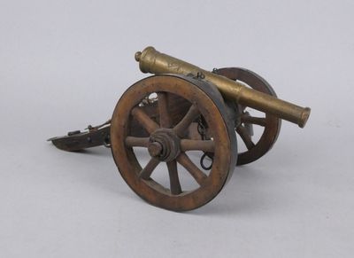 a small bronze cannon sitting on top of a wooden wheel