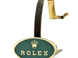 un gros plan sur un logo Rolex accroché à un crochet, sur fond blanc