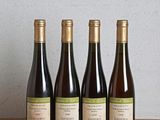 trois bouteilles de vin sont alignées sur une table en bois
