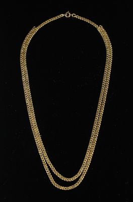 un collier à chaîne en or avec une pièce de monnaie sur fond noir