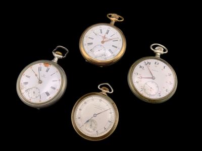 quatre types différents de montres de poche posées sur une surface noire