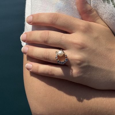 une femme tenant une bague ornée d'une perle
