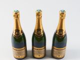 three bottles of champagne sitting next to each other on a white surface