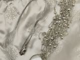a silver watch and a silver bracelet on a white satin bag