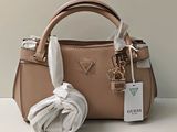 un sac à main en cuir beige avec un foulard blanc posé sur une table blanche