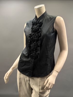mannequin vêtu d'une chemise noire et d'un pantalon beige orné d'un volant noir