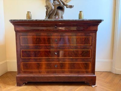 a wooden chest of drawers with a statue on top of it