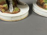 pair of porcelain figurines of a man and a woman sitting on a tree stump
